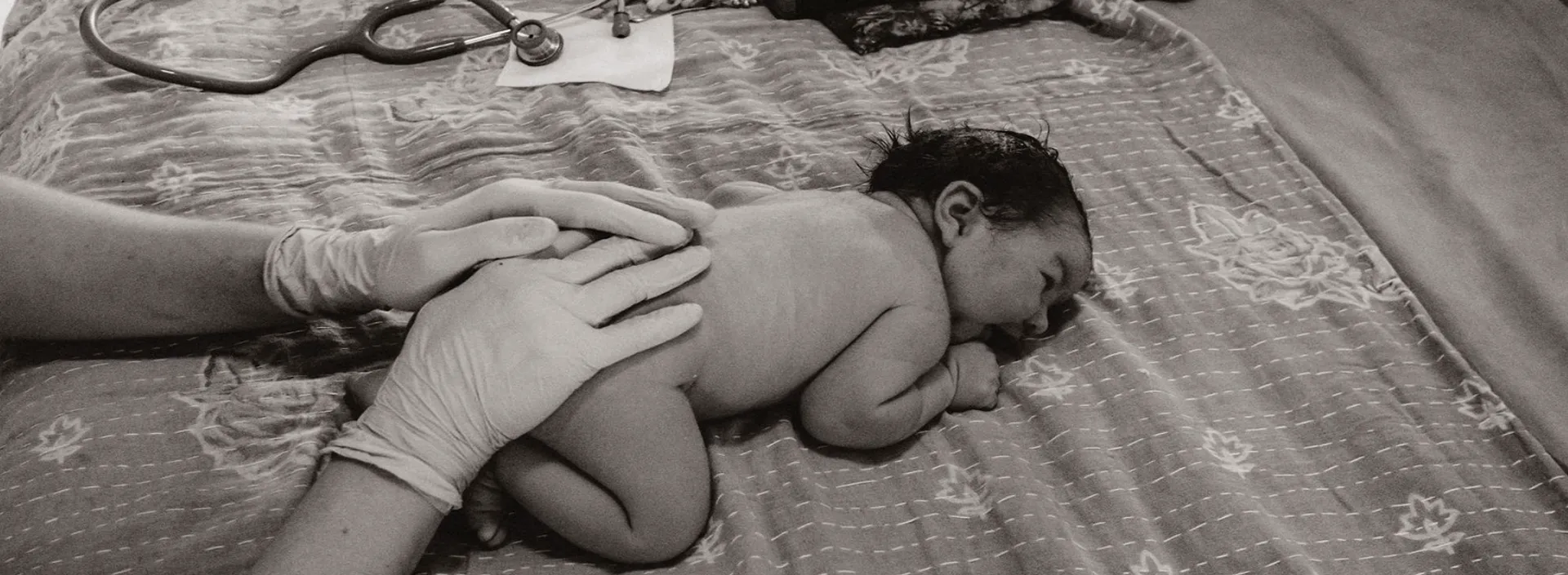Swaddled newborn resting in supportive hands